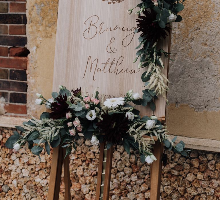 Wooden wedding sign decorated with burgundy wedding flowers and foliage 