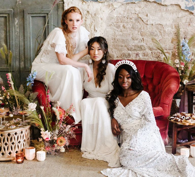 three brides sitting on a red velvet sofa at The Asylum, London 