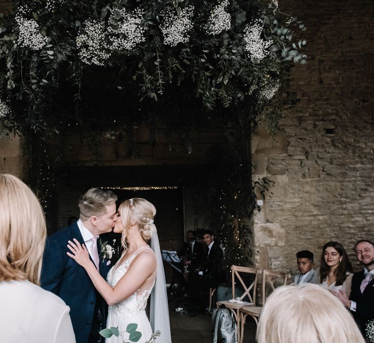 Bride and groom kissing at spring barn wedding with vintage theme