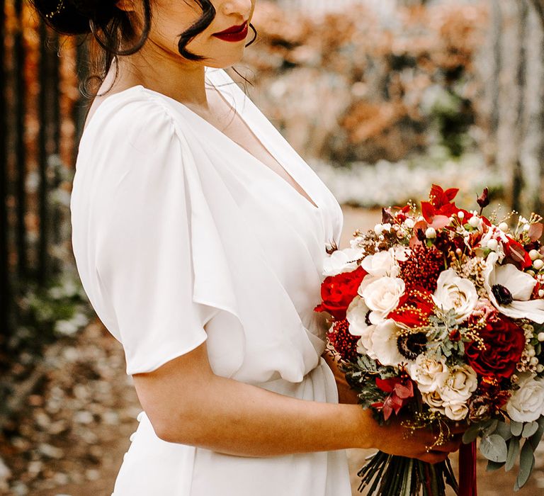 Bride with wedding hair updo with flowers and red rose bouquet