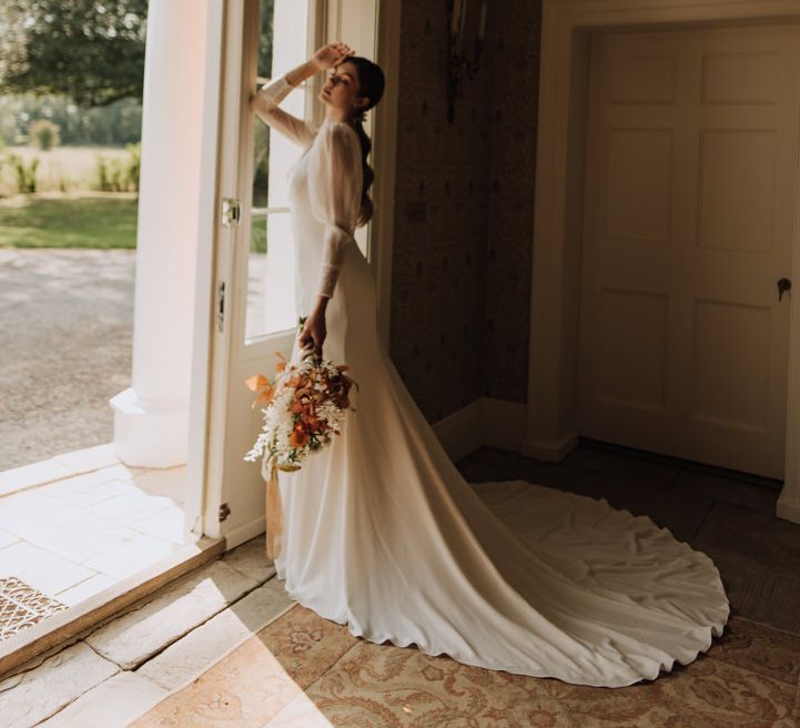 Bride holding autumnal bouquet at Reymerston Hall