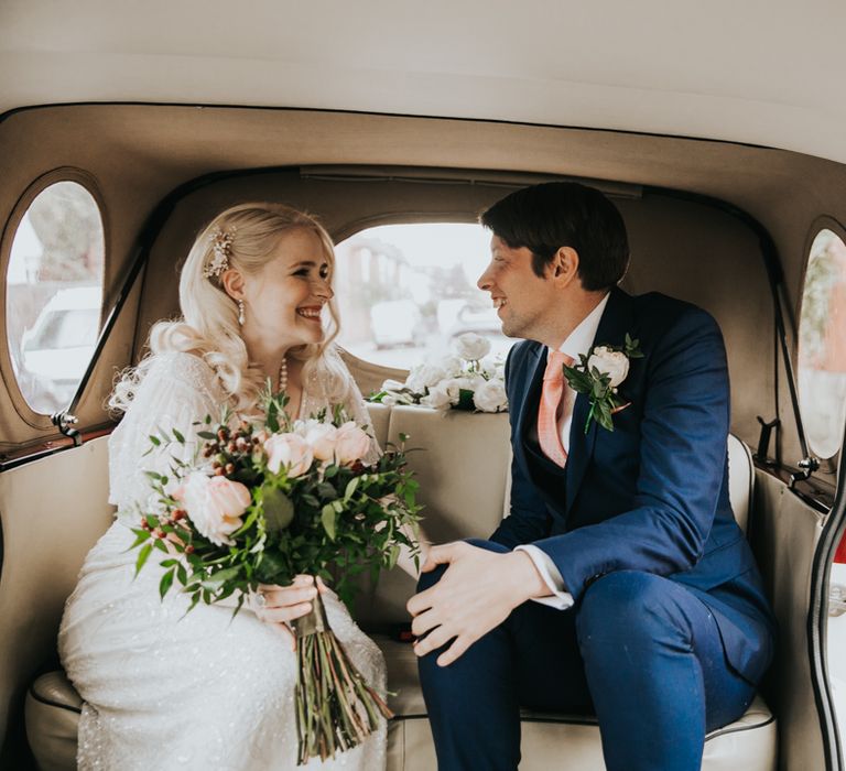 Bride & groom sit in wedding car during wedding day 