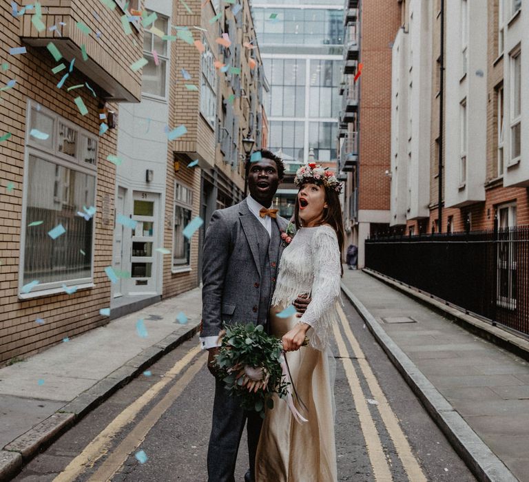 Wedding couple look surprised as confetti falls down on them