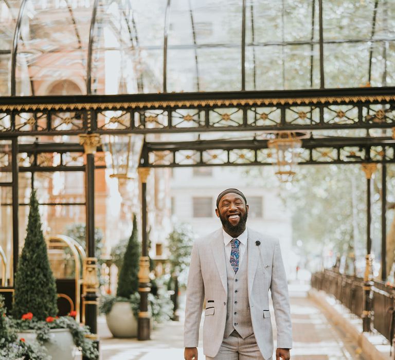 Stylish black groom in light grey suit outside The Landmark London wedding venue 