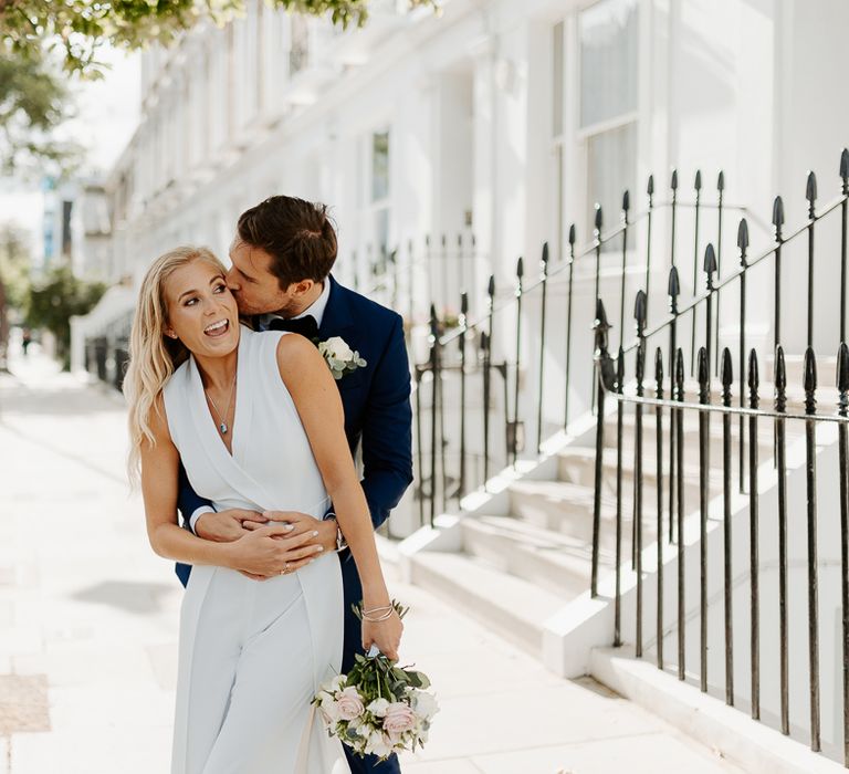 Groom embraces bride from behind in London