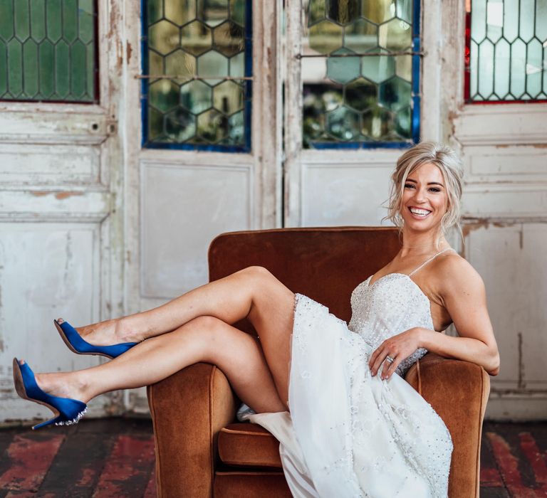 Bride sits back and shows off blue heels in chair 