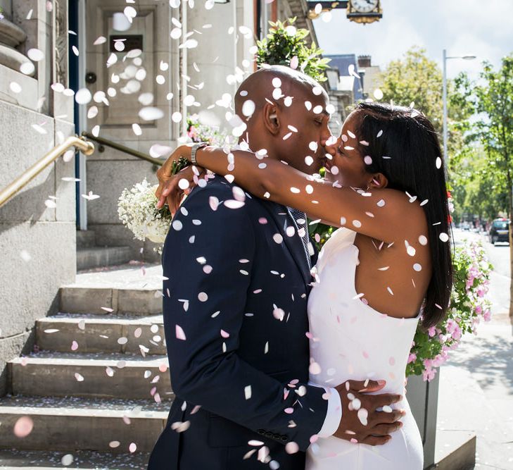 Confetti moment with bride and groom kissing outside Chelsea Town Hall