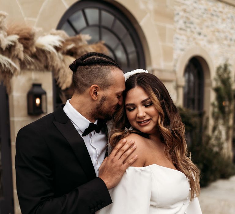 Intimate bride and groom portrait with groom in a tuxedo and bride in a strapless wedding dress with balloon sleeves 