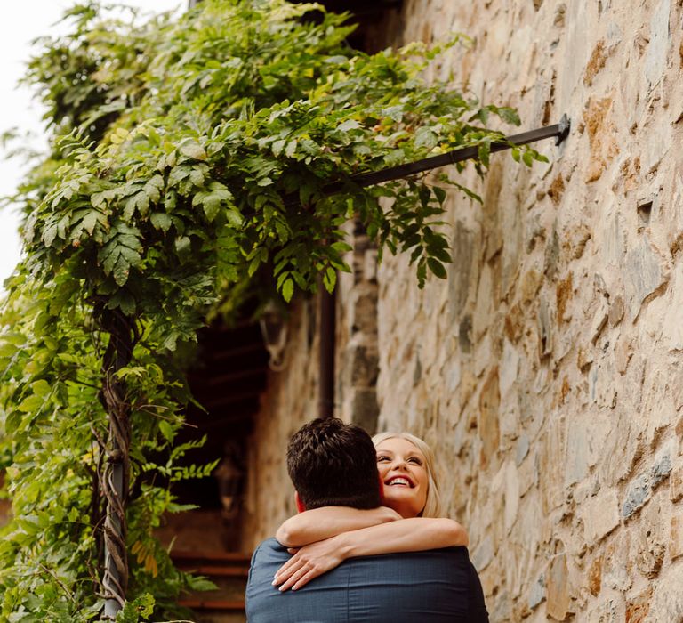 The bride and groom hugging on a staircase after their first look moment, the bride has a huge smile on her face