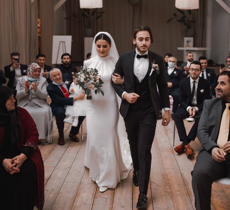 Bride & groom walk down the aisle with one another on wedding day