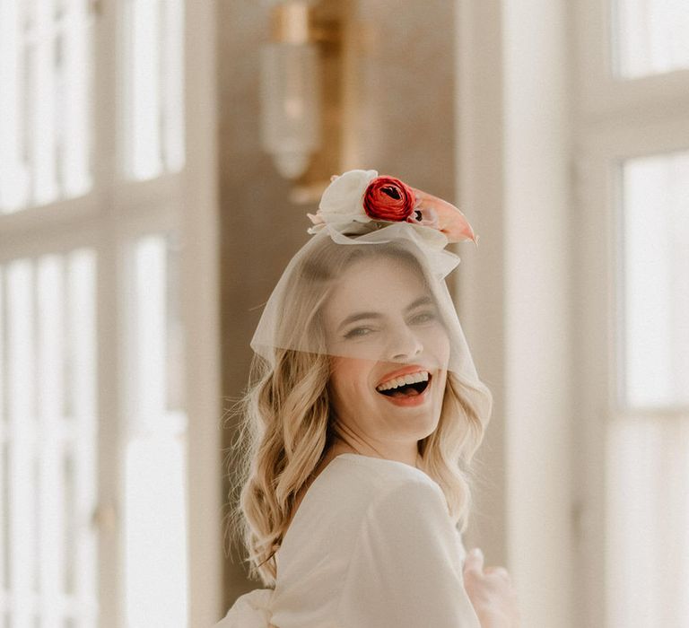 Bride wearing a long sleeve mid length wedding dress with sequin skirt detail, and a short mesh veil covering her face with flowers on her head