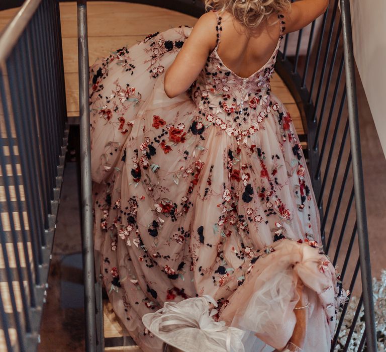 Bride walks up the stairs and wears blonde hair in low up-do with pearl hair accessories 