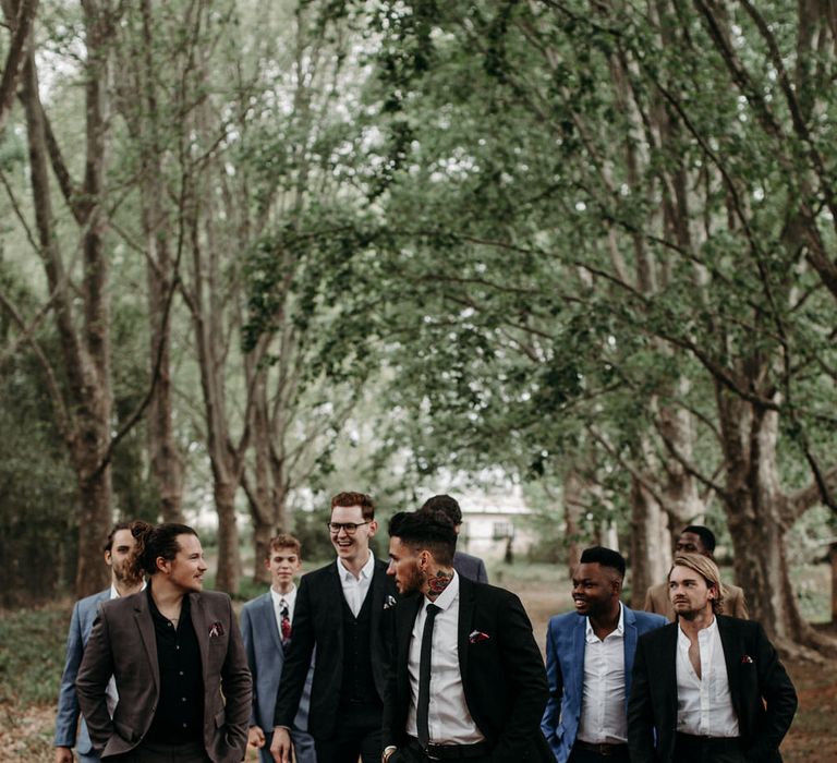 Groom and groomsmen in assorted suits, in the South African countryside