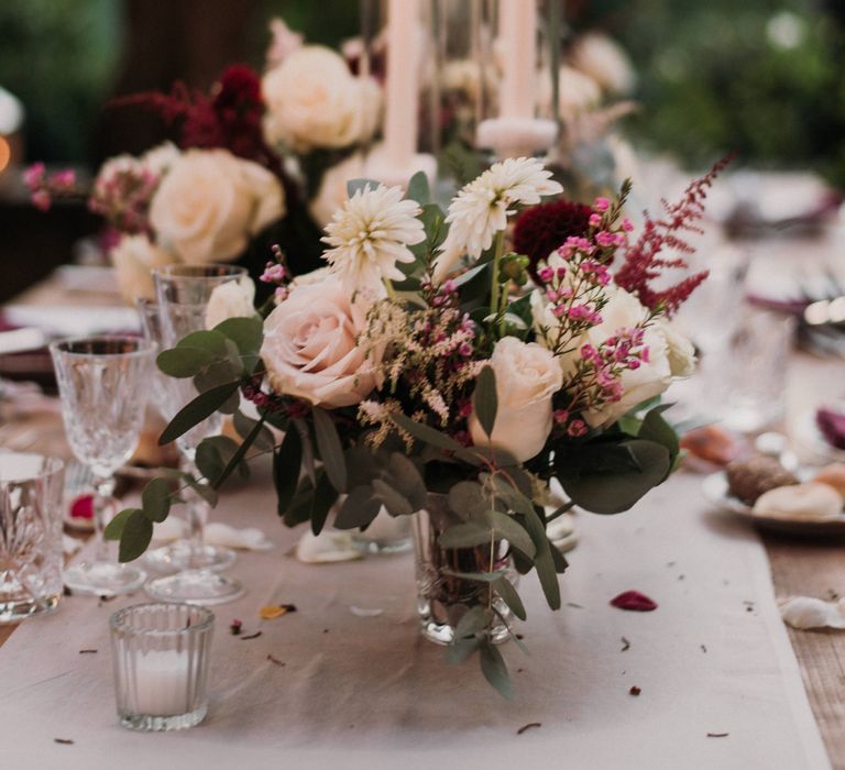 White, red and pink floral bouquet surrounded by candlelight 