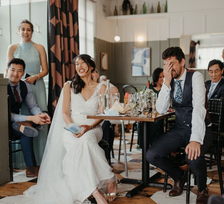 The bride and groom laughing at speeches