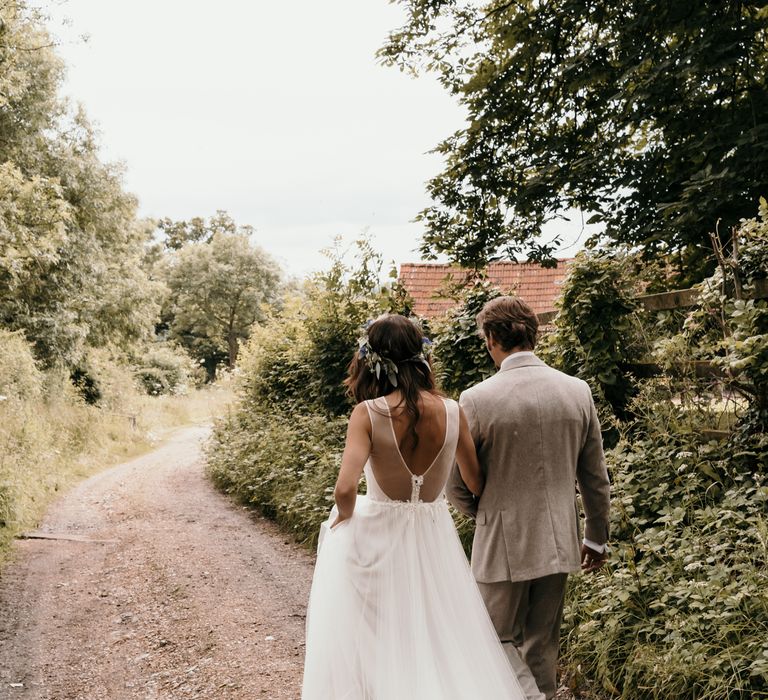 Bride & groom wander down road on the day of their wedding 