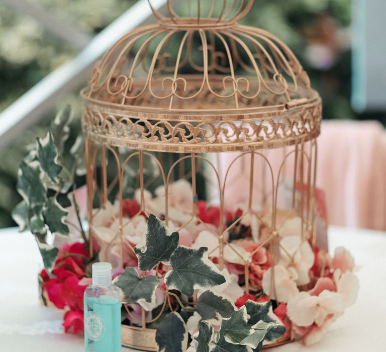 Rose gold cage decoration filled with brightly coloured flowers 