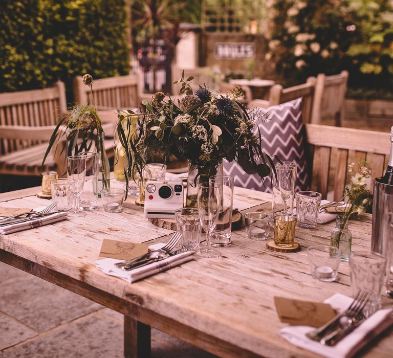 Intimate London pub wedding reception with blue and white floral centrepieces on rustic tree slices, votives, tea lights a polaroid camera