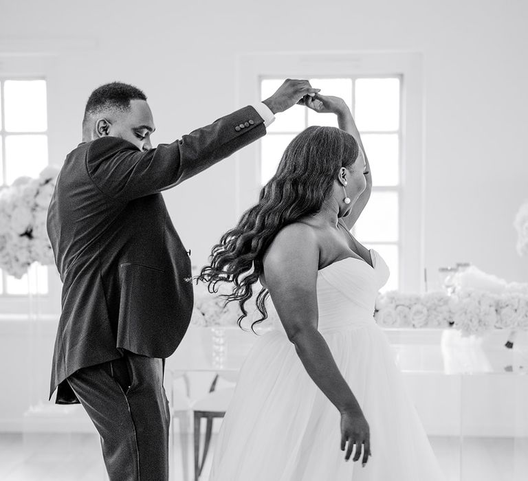 Groom spins around his bride on wedding day in black & white image