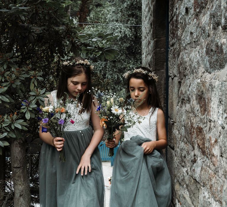 Flower girls wear green dresses and colourful flower gowns whilst holding bouquets