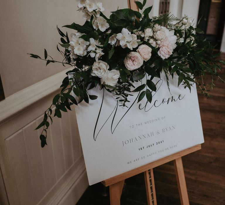 Wedding stationery in classic white surrounded by white florals and green foliage