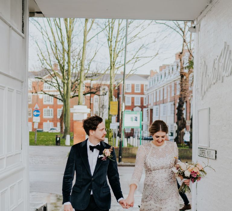 Bride & groom walk hand in hand outside after wedding ceremony