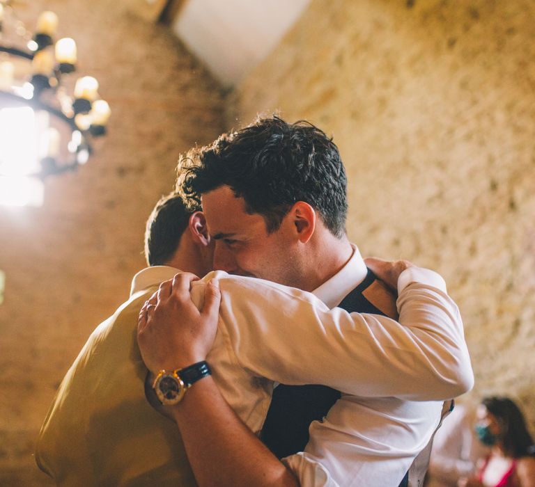 Grooms hug at Stone Barn on their wedding day | Story + Colour