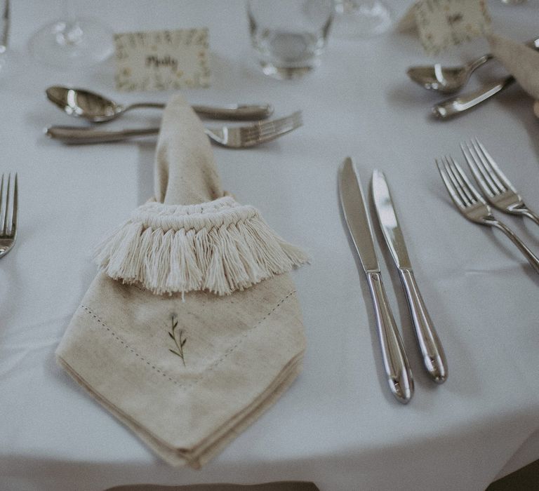 White wedding breakfast table with silverware, glassware and leaf embroidered napkins with macrame napkin tie for Isle of Wight wedding with macrame wedding decor