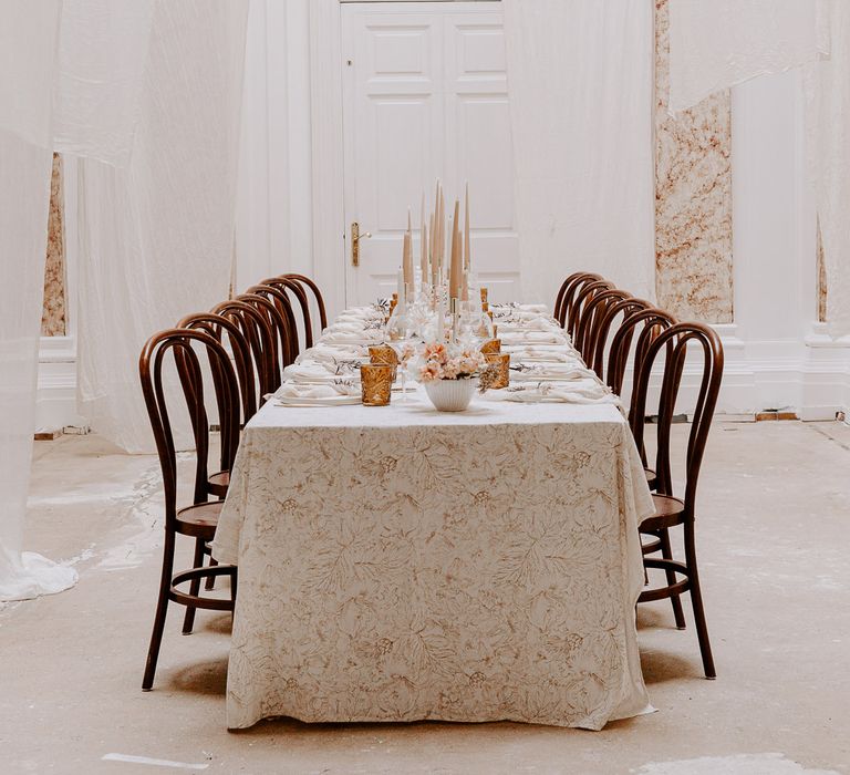 Minimal wedding inspiration at Bylaugh Hall with neutral colour palette, patterned table cloth and taper candles 