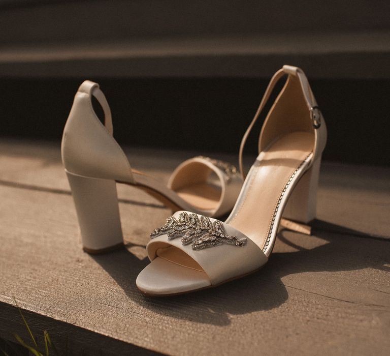 White heeled sandals with beaded leaf detail on strap on wooden step at Inkersall Grange Farm wedding 