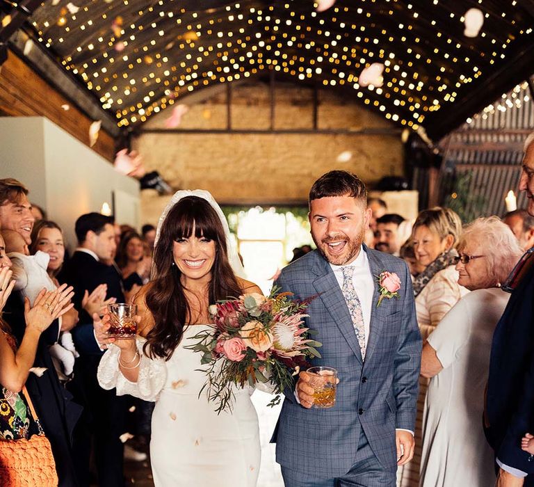 Bride & groom walk down the aisle as bride wears Rime Arodaky dress with puffed sleeves and gold Miu Miu platform sandals 