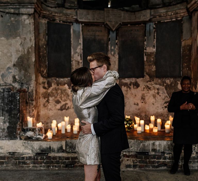 Edgy Bride and Groom kiss in front of candles 