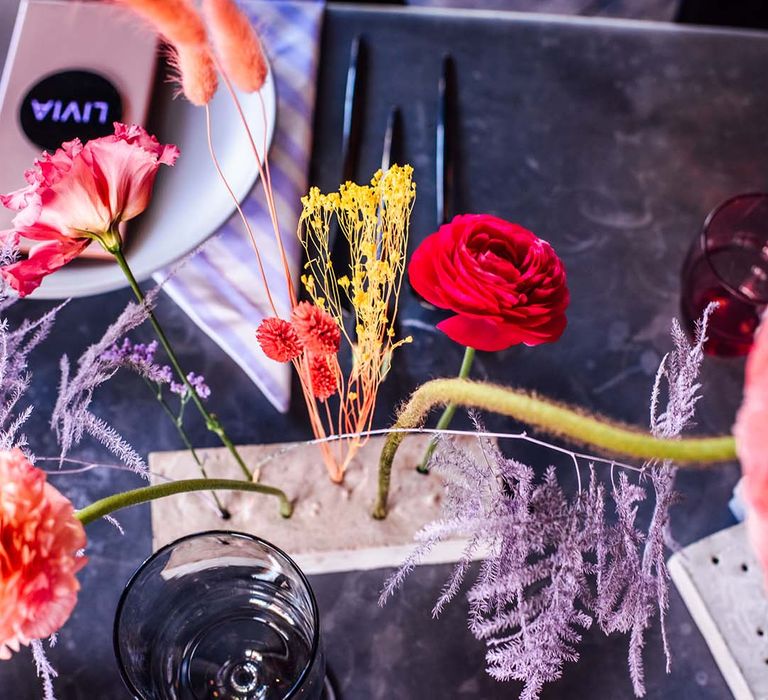 coloured glassware and flower stems in concrete plinths wedding table decor 