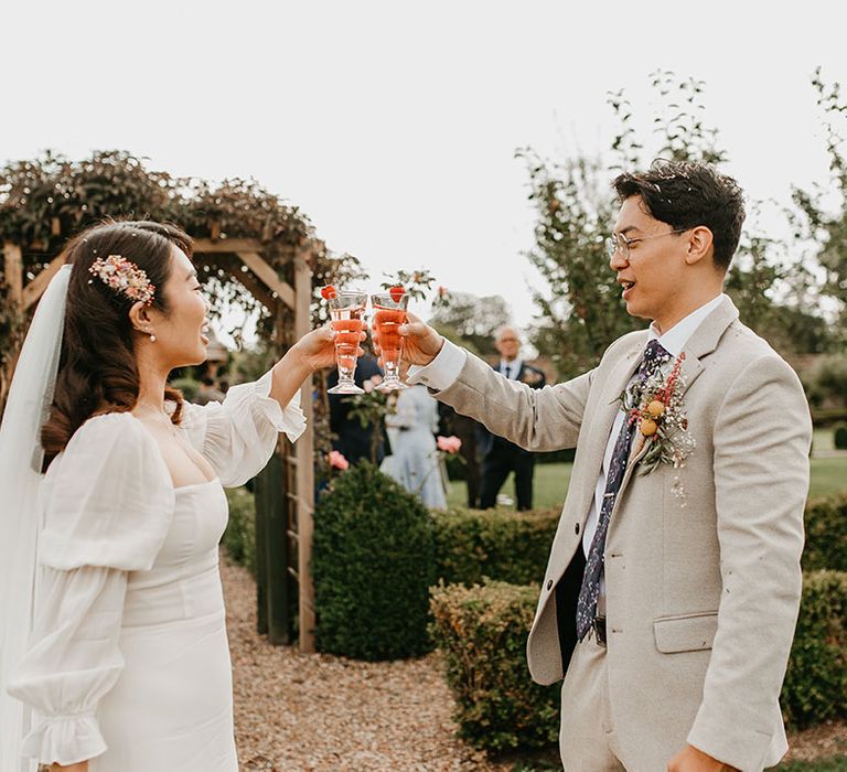 Bride & groom cheers drinks outdoors after wedding ceremony