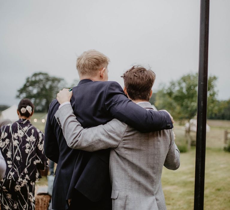 Groom wraps his arm around wedding guest on his wedding day