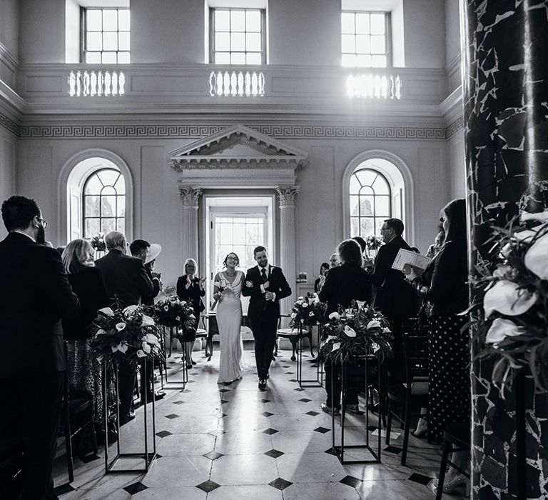 Bride walks with her groom in black & white image 