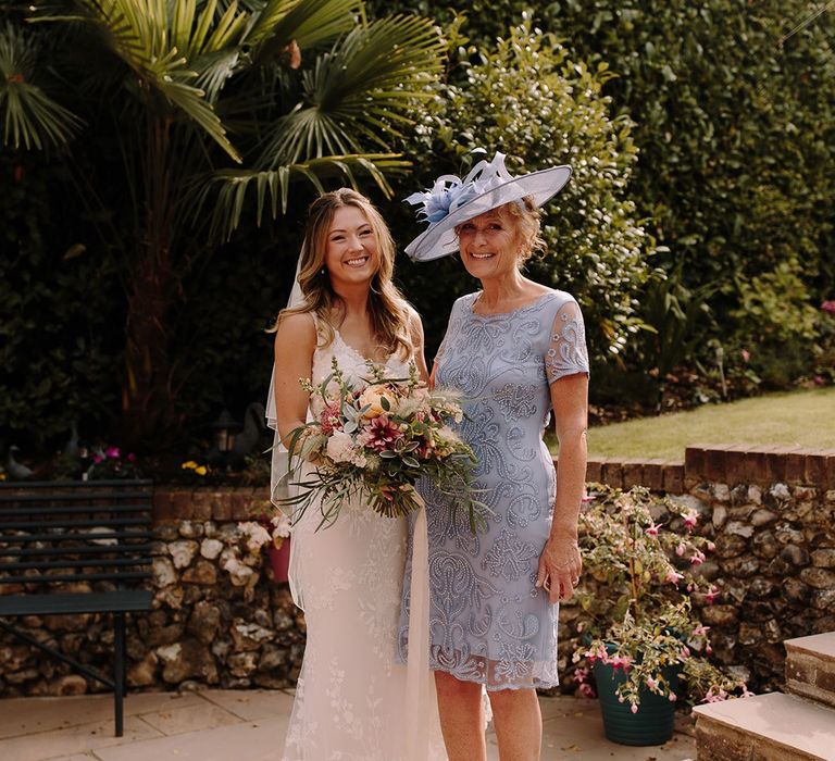 Bride with mother of the bride in blue lace dress and matching hat