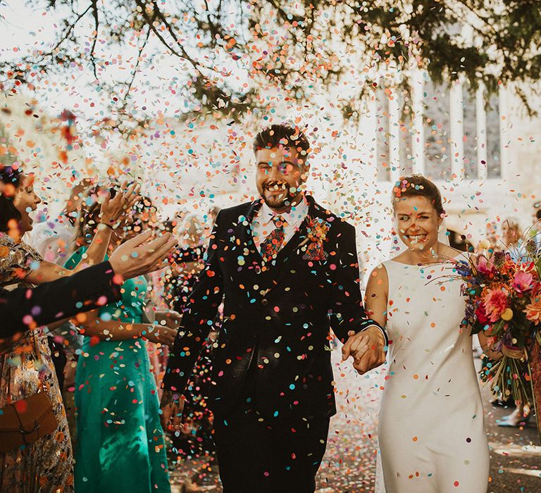 Colourful wedding confetti moment in a church courtyard 