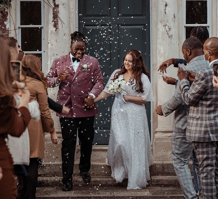 Bride & groom leave as wedding guests throw confetti around them