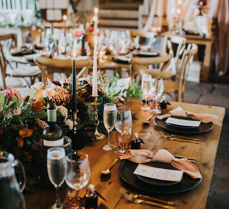 autumn theme wedding table decor with black tableware, gold cutlery and taper candles 