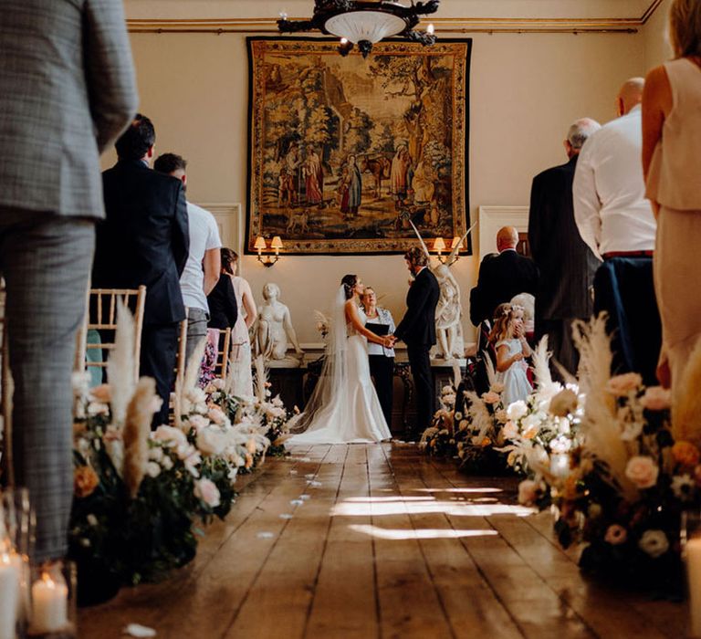 Couple in black tuxedo and mermaid fishtail wedding dress exchanging their vows at Elmore Court