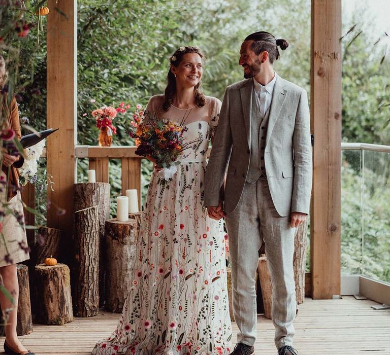 Bride and groom at the altar for their outdoor wedding with tree trunk candle holders and hanging plant decor