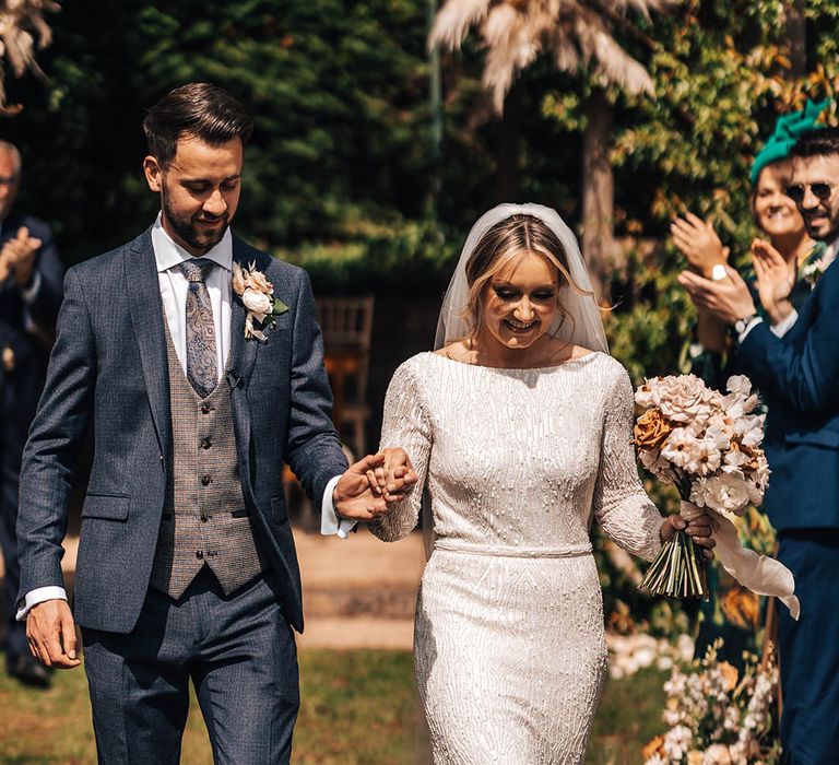 Bride and groom exit their outdoor ceremony together at Pennard House