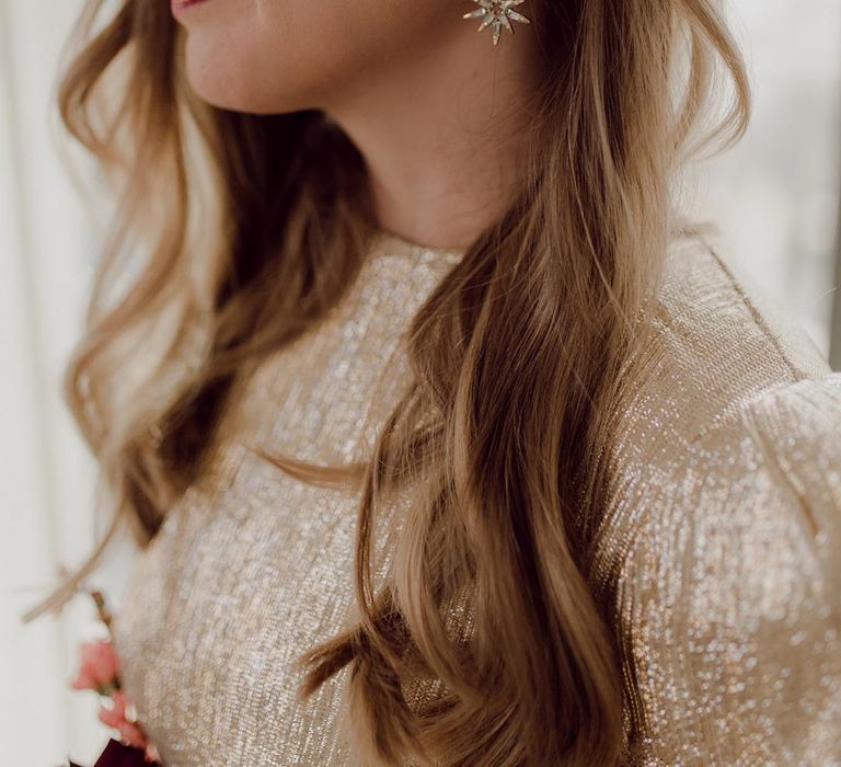 Bride with pearl hair clip accessory and star earrings with gold eye makeup and gold wedding dress