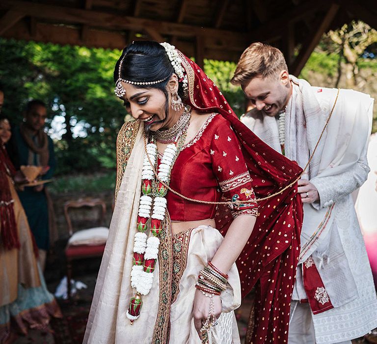 Bride and groom in traditional Indian wedding attire with bride wearing gold jewellery including headdress, bangles and necklaces