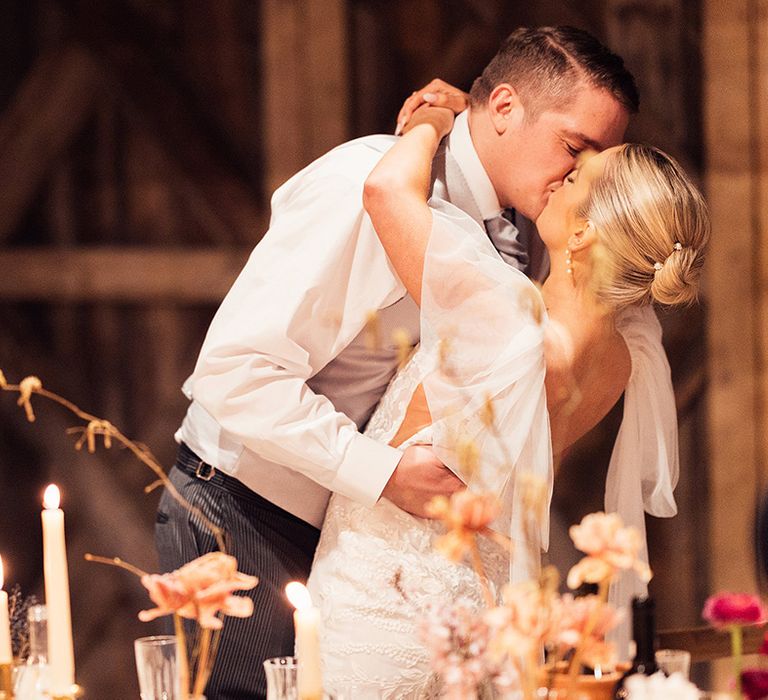 Groom leans the bride back as they share a kiss during their wedding reception