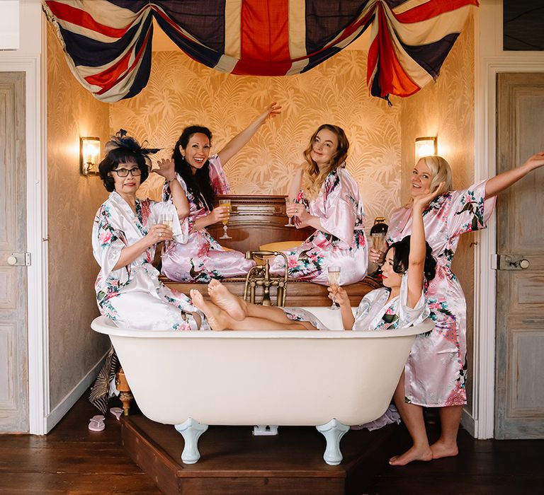 Bride with bridesmaids and mother of the bride in pink and white flower satin robes while they get ready for the wedding 