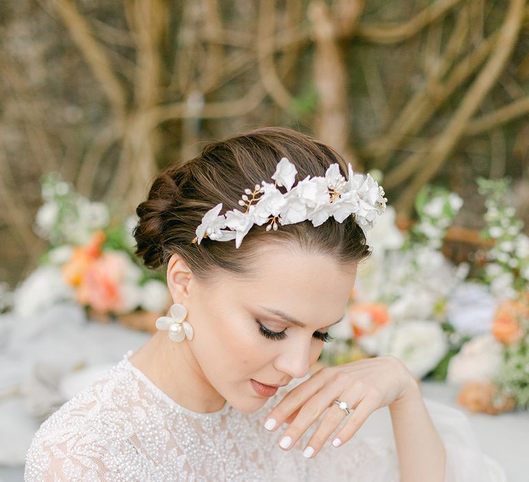 bride in a beaded wedding dress with white nails polish, solitaire diamond engagement ring wearing a stylish headband and earrings bridal accessories 