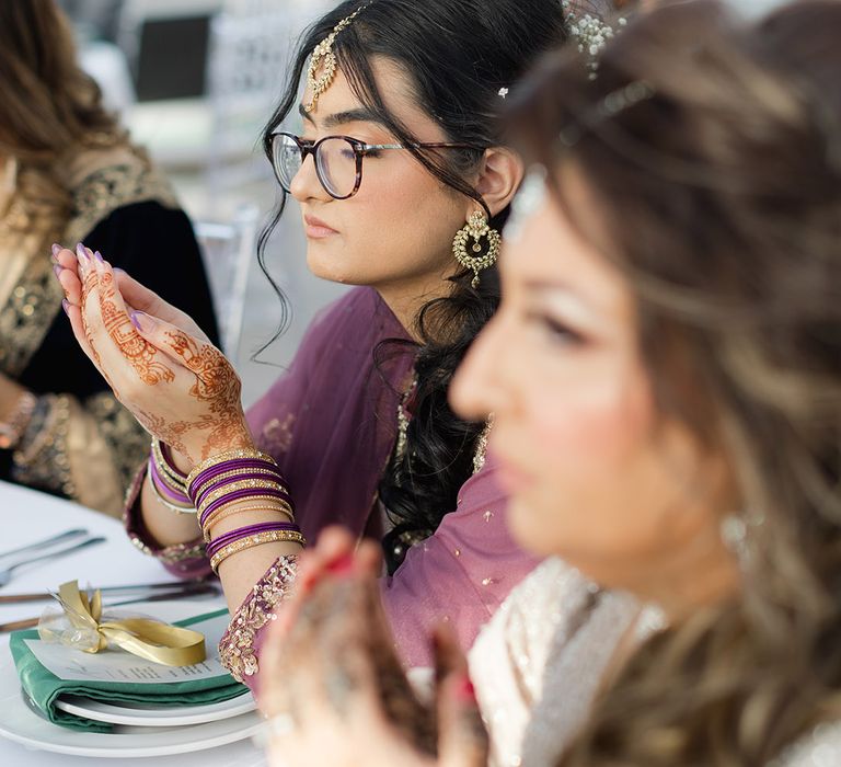 Wedding guests cup hands together at table during reception 