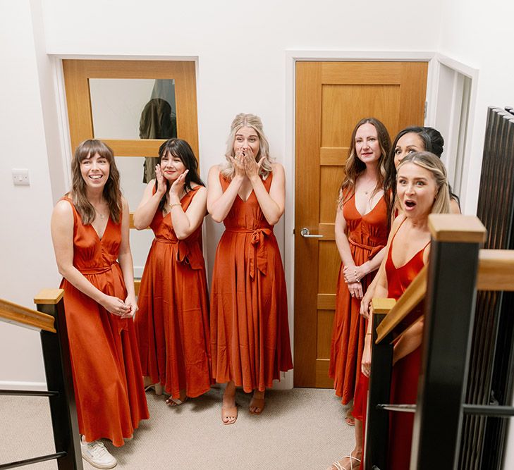 Bridesmaids wearing orange silk slip dresses see bride for the first time 